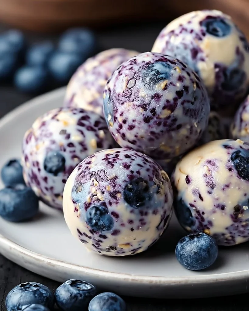 Blueberry Cheesecake Protein Bites on a plate with fresh blueberries