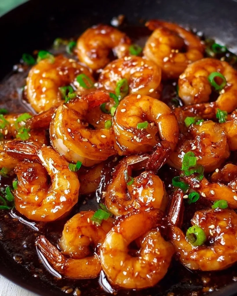 Delicious easy sticky honey garlic shrimp served in a bowl with garnishes.