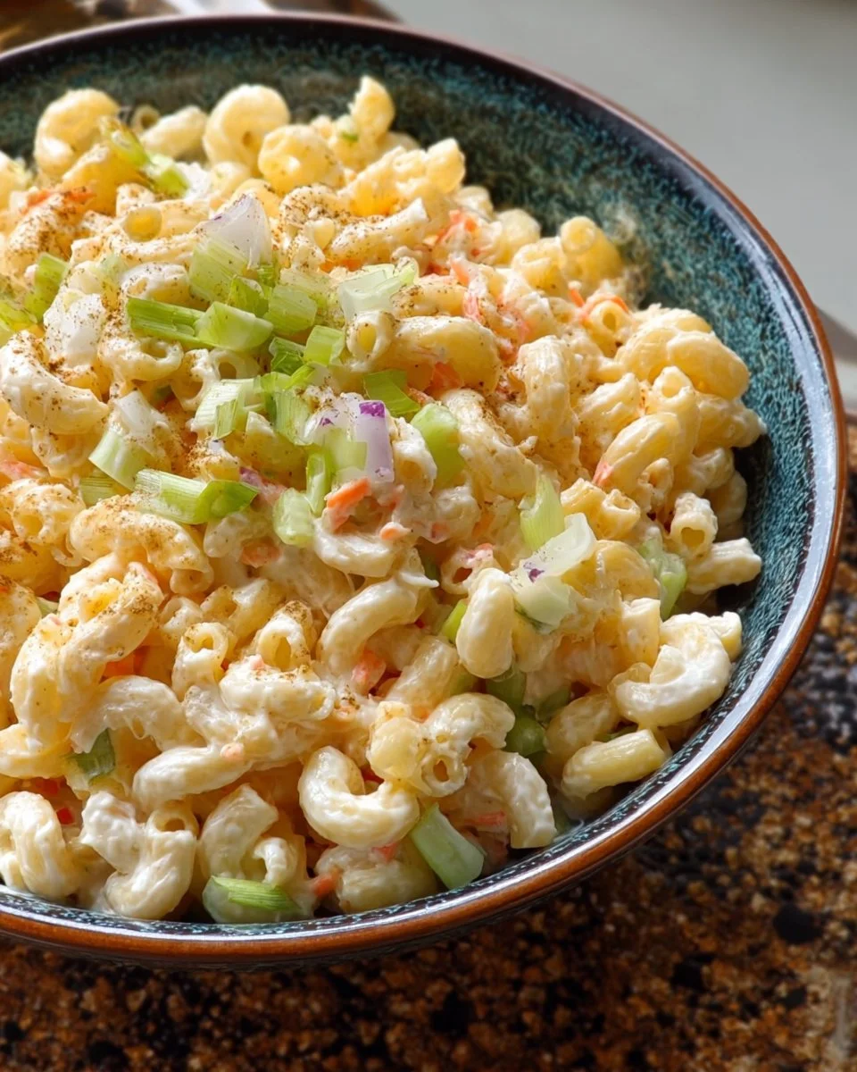 A bowl of Hawaiian Macaroni Salad garnished with green onions and carrots.