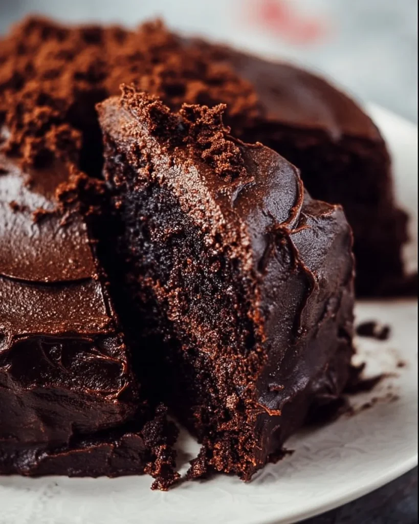 Delicious slice of amazing chocolate cake topped with creamy frosting and chocolate shavings.