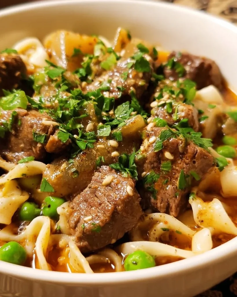 A delicious plate of beef and noodles garnished with fresh herbs and vegetables.