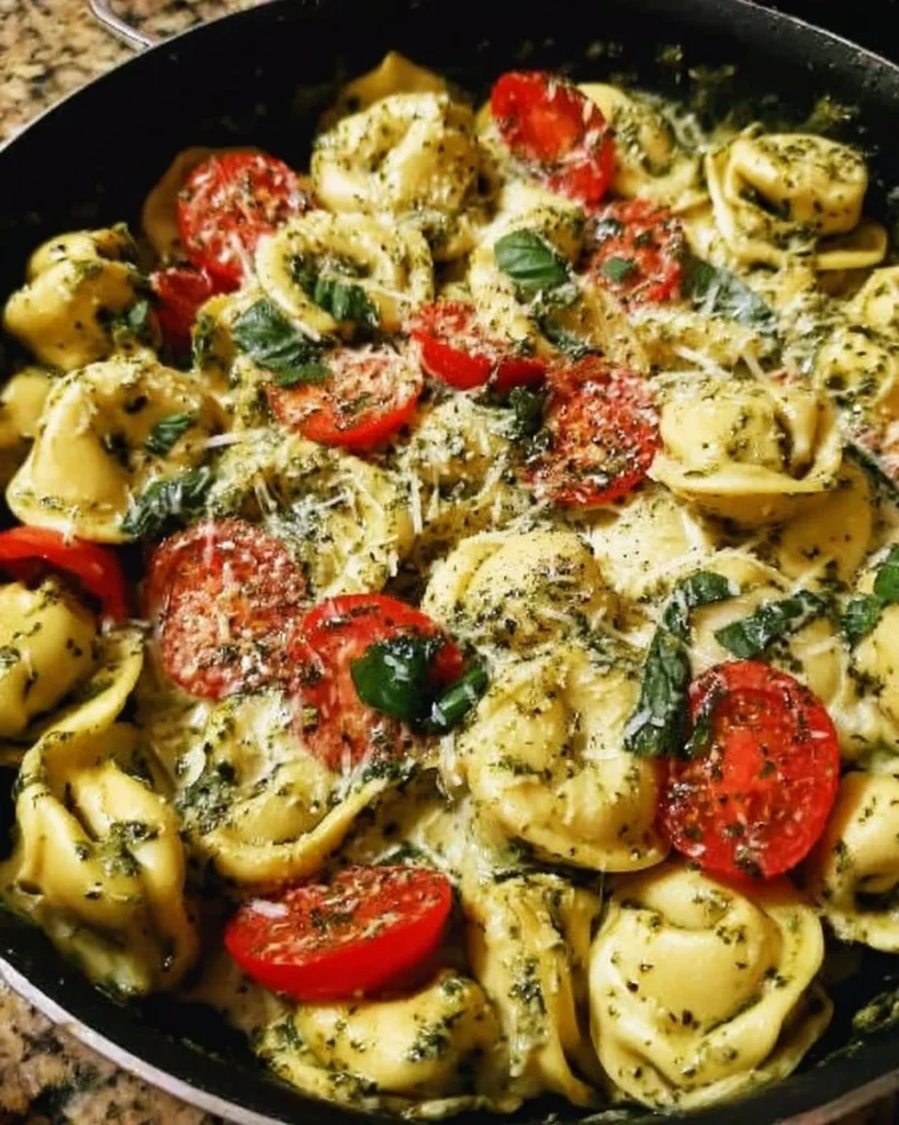 Creamy pesto tortellini skillet dish garnished with fresh basil