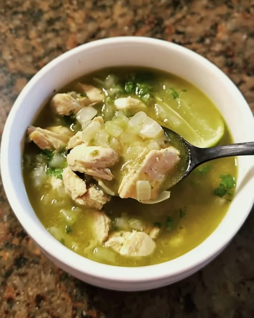 Bowl of easy green chicken pozole garnished with cilantro and lime