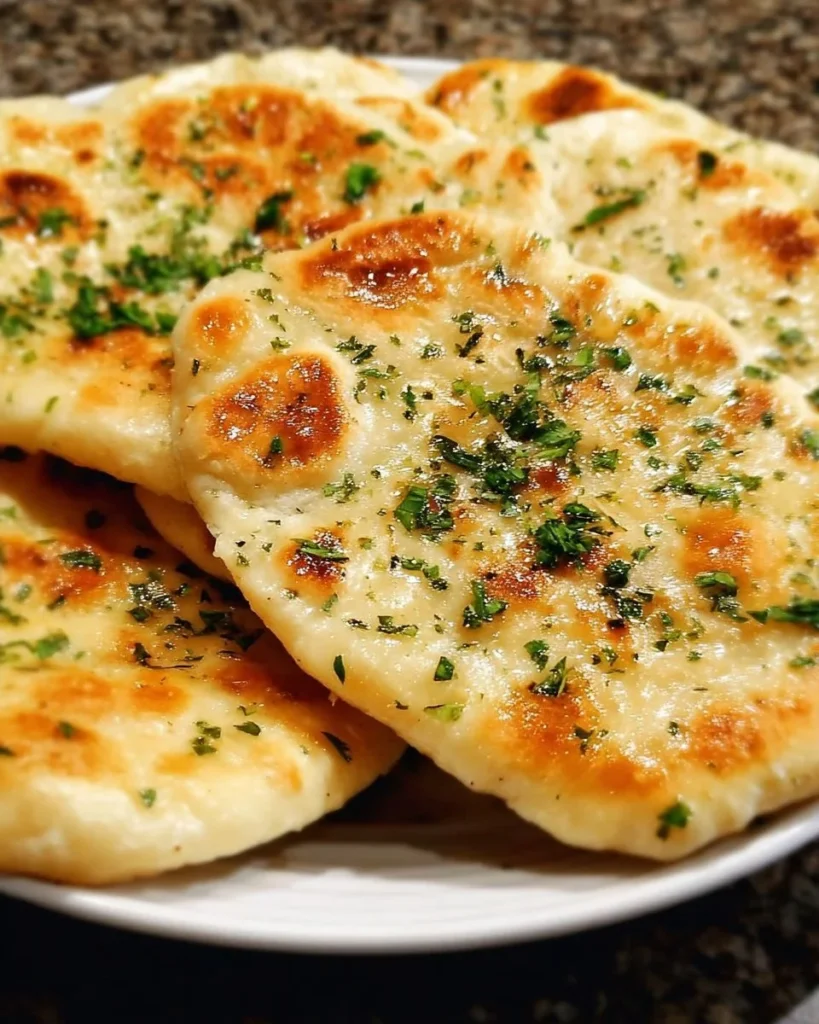 Freshly baked homemade naan flatbread served with dipping sauce.