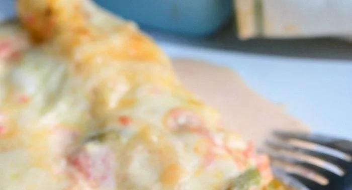 Plate of creamy shrimp enchiladas topped with sauce and cheese