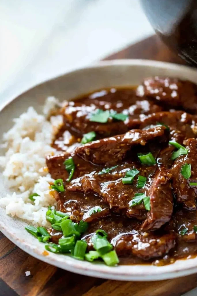 Delicious Slow Cooker Mongolian Beef served with rice and vegetables.
