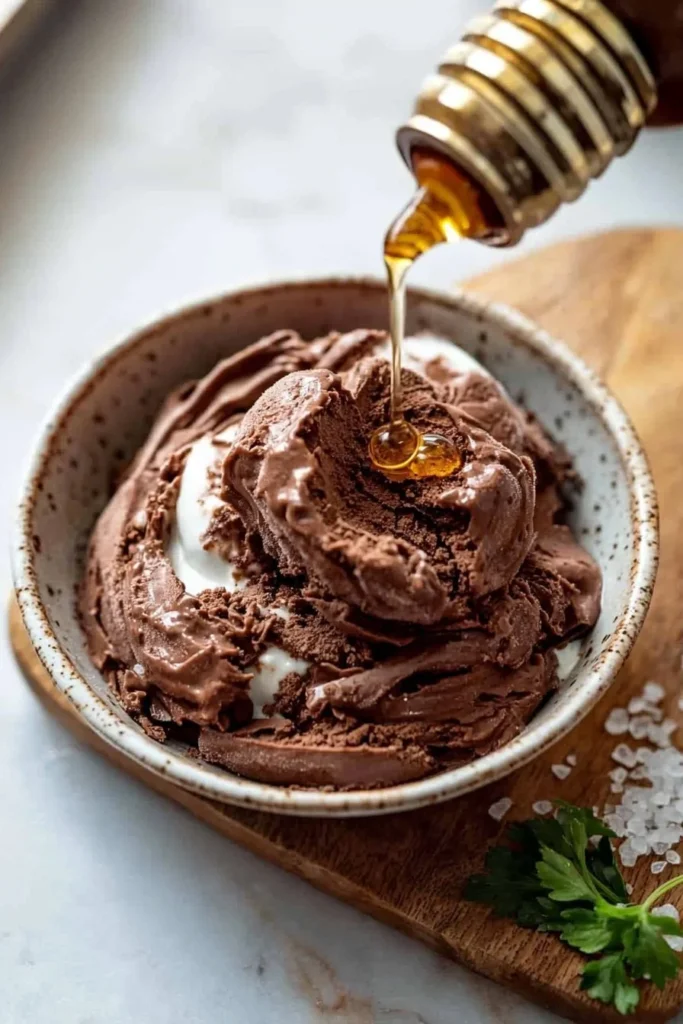 A bowl of frozen Greek chocolate yogurt topped with chocolate shavings and fresh fruit.