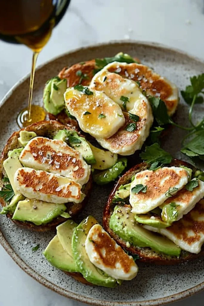 Halloumi, honey, and avocado bagel served on a rustic wooden table