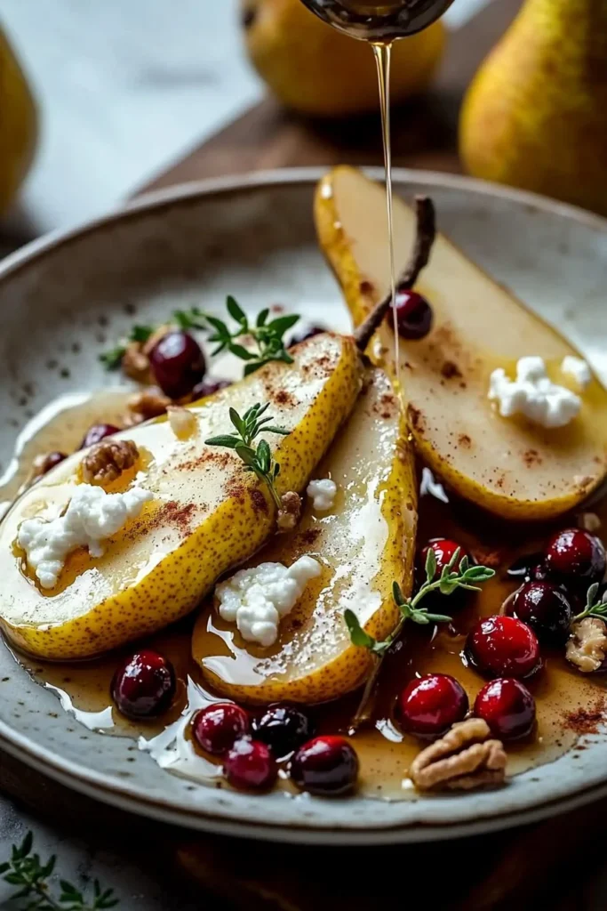 Baked pears topped with goat cheese, honey, and cranberries in a serving dish.