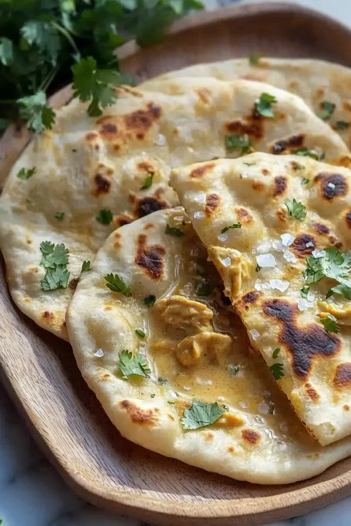 Flatbread topped with creamy butter chicken and garnished with herbs