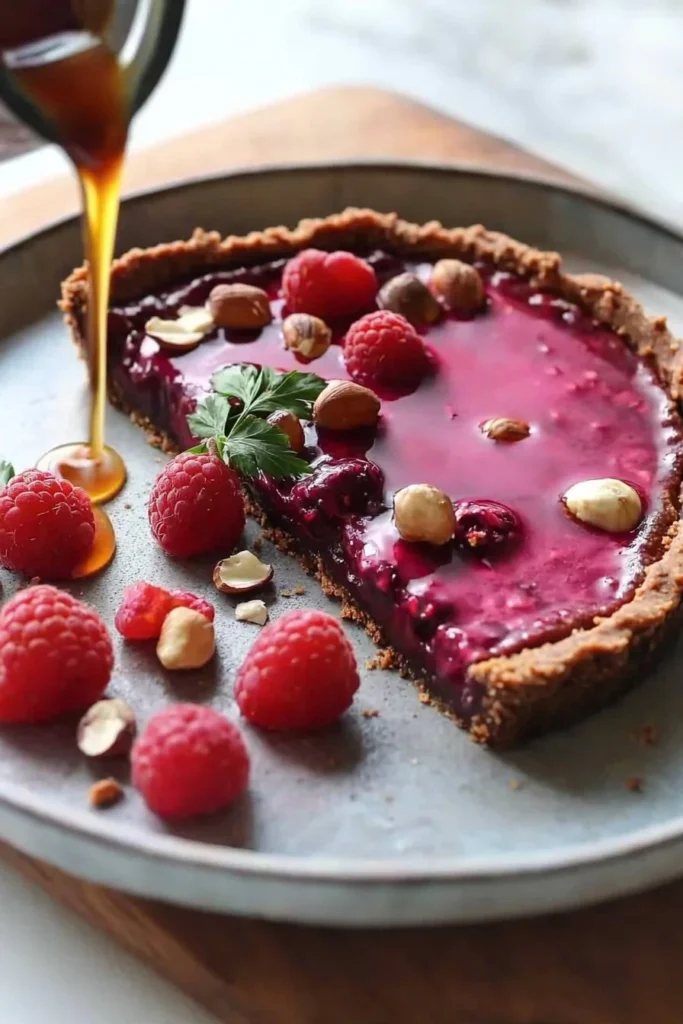 No bake raspberry tart with hazelnut cacao crust on a white plate